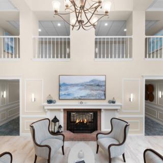 A luxurious living room featuring a central fireplace, elegant seating, and a chandelier.