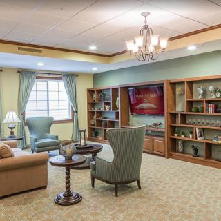 A cozy living room with traditional decor, featuring comfortable seating and bookshelves.