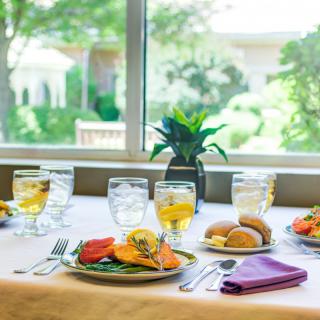 A beautifully set dining table with a meal, glasses of beverage, and elegant tableware.