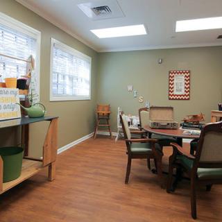 A cozy dining area with tables and chairs, featuring large windows and wooden flooring.