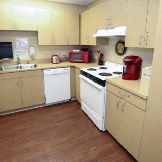 A modern kitchen with wooden cabinets, featuring a stove, microwave, coffee maker, and dishwasher.