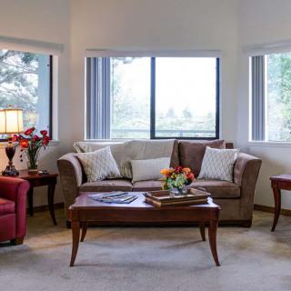 A cozy living room with a sofa, armchair, and coffee table set near large windows.