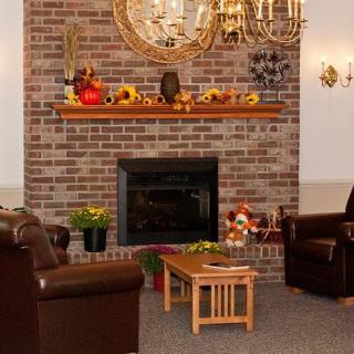 A cozy living room with a brick fireplace, leather chairs, and autumn decorations.