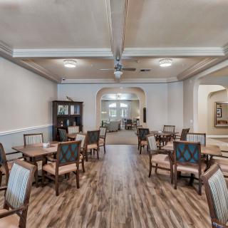 An elegant dining room with neatly arranged tables and chairs on a polished wooden floor.