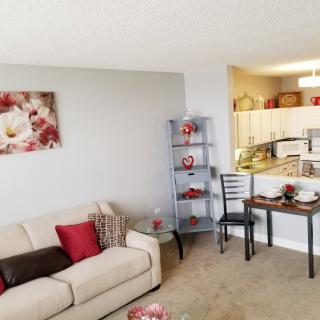 A cozy living room with a sofa, decorative shelves, and a view into the kitchen area.