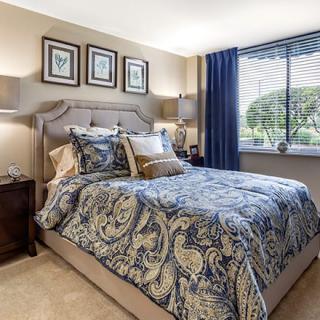 A well-decorated bedroom featuring patterned bedding and neutral-colored walls.