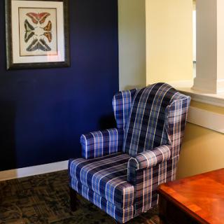A cozy plaid armchair set against a dark blue wall, complemented by framed artwork.