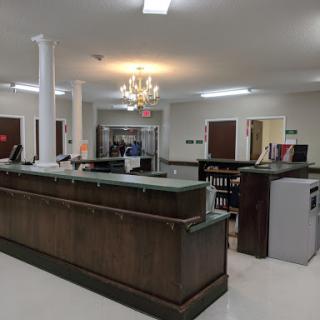 A spacious reception area featuring a wooden counter, elegant chandelier, and modern office furnishings.