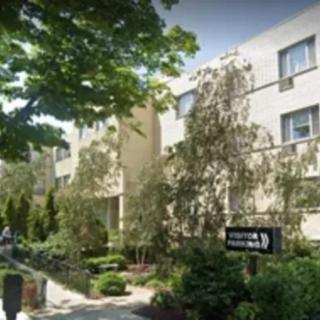 A street view of a residential apartment building surrounded by trees.
