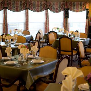 An elegant dining room with neatly arranged tables and chairs, complete with napkin settings.