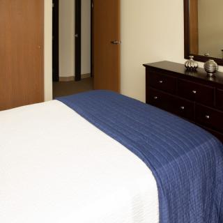 A neatly arranged bedroom with a bed, dresser, and mirror.