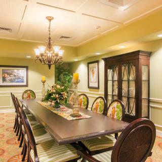 A well-decorated dining room with a long table, elegant chairs, and a chandelier.