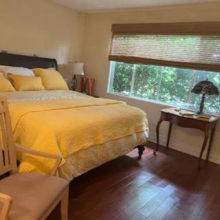 A cozy bedroom with yellow bedding and a large window.