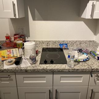 A cluttered kitchen countertop with various groceries and cooking items.