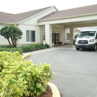 The welcoming entrance of a hospitality facility with a parked van and well-maintained landscaping.