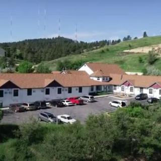 A hotel with a parking lot, surrounded by rolling hills.