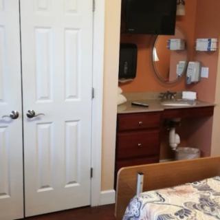 A cozy bedroom featuring a closet, television, and dresser.