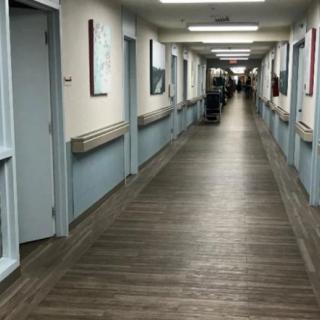 A long, empty hallway with doors on either side and overhead fluorescent lighting.