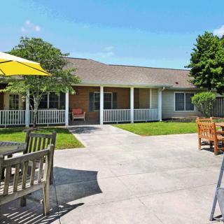 A sunny courtyard with patio furniture and an umbrella in front of a house.