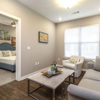 A modern living room with a sofa, coffee table, and decor, adjacent to a bedroom.