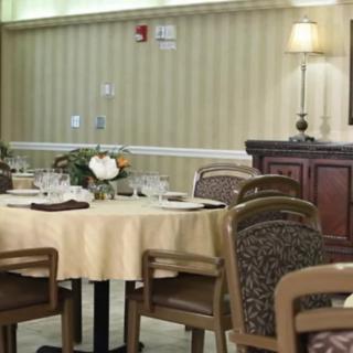 A neatly set dining area with round tables and upholstered chairs.