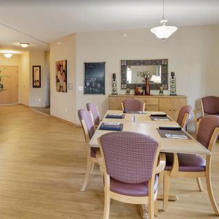 A modern dining room with a wooden table and chairs, featuring elegant lighting and decor.