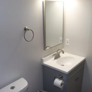 A minimalist bathroom with a sink, mirror, and toilet.