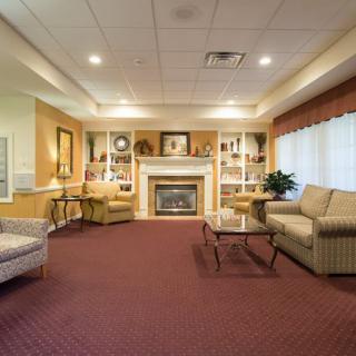 A cozy and elegantly furnished living room with a fireplace, sofas, and large windows.