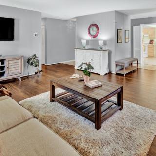 A modern living room with a wooden floor, decorated with a sofa, coffee table, and a wall-mounted television.