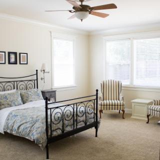 A serene and stylish bedroom featuring a black wrought iron bed and comfortable seating.