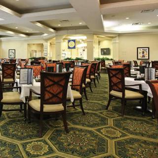 An elegantly designed dining area with neatly arranged tables and chairs, featuring a patterned carpet.