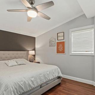 A minimalist bedroom with a large bed, ceiling fan, and wall decor.