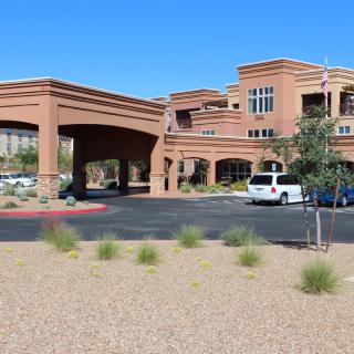 A modern building with an entrance and a parking area in a desert landscape.
