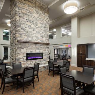 A modern dining area featuring a large stone fireplace and elegant lighting fixtures.