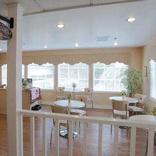 A bright and modern cafeteria interior with tables and chairs arranged near large windows.