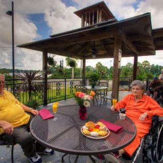 Two seniors enjoying a meal on an outdoor patio.