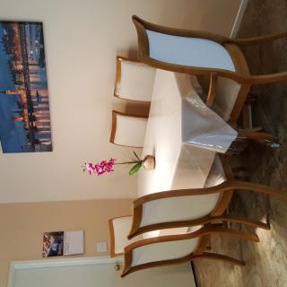 A dining room with a table, six chairs, and an orchid centerpiece beneath a wall painting.