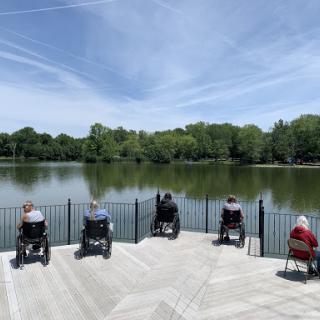 Seniors enjoying the serene view of the lake from their wheelchairs on a beautiful day.
