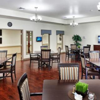 A clean and spacious dining room with neatly arranged tables and chairs on a hardwood floor.