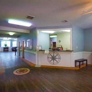 A spacious lobby with a reception area featuring wooden flooring and modern decor.