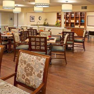 A spacious dining room with neatly arranged tables and chairs, featuring warm lighting and elegant decor.