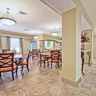 A spacious dining room with elegant tables and chairs, well-lit with overhead lighting.