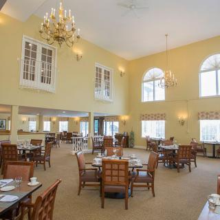 A spacious and elegant dining room with chandeliers, ample seating, and large windows that let in natural light.