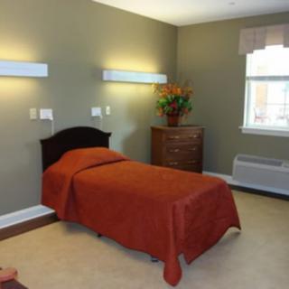 A minimalist bedroom with a single bed, bedside lamp, and a window.