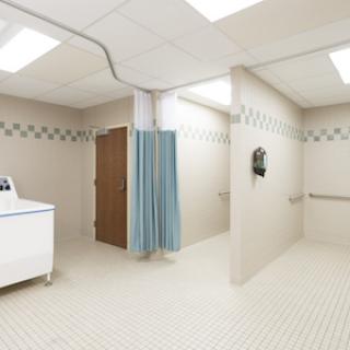 A clean and spacious medical bathroom equipped with a wash basin, privacy curtains, and disability-accessible features.
