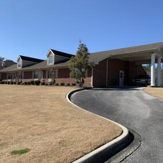 A view of a modern building with a curved driveway under a clear blue sky.