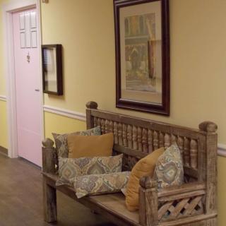 A cozy hallway with a wooden bench adorned with patterned pillows and framed artwork on the wall.