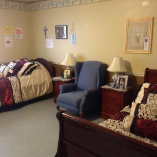 A cozy bedroom with two beds, an armchair, and nightstands with lamps.