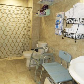 An accessible bathroom with a shower, toilet, and various assistive devices.