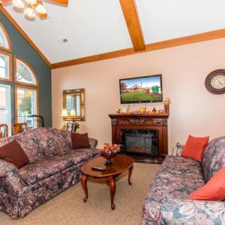 A cozy living room with floral sofas, a fireplace, and a television above it.